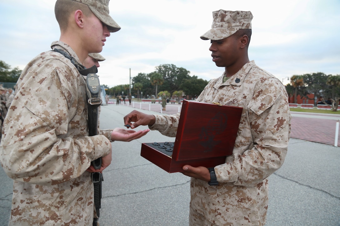 Staff Sgt. John Sharpe, a drill instructor with Platoon 1005, Charlie Company, 1st Recruit Training Battalion, hands a new Marine his Eagle, Globe and Anchor after completing the Crucible hike on Marine Corps Recruit Depot Parris Island, S.C., Dec. 22, 2018. The Crucible is a 54-hour culminating event that requires recruits to work as a team and overcome challenges in order to earn the title United States Marine. (Official Marine Corps photo by Cpl. Sarah Stegall)