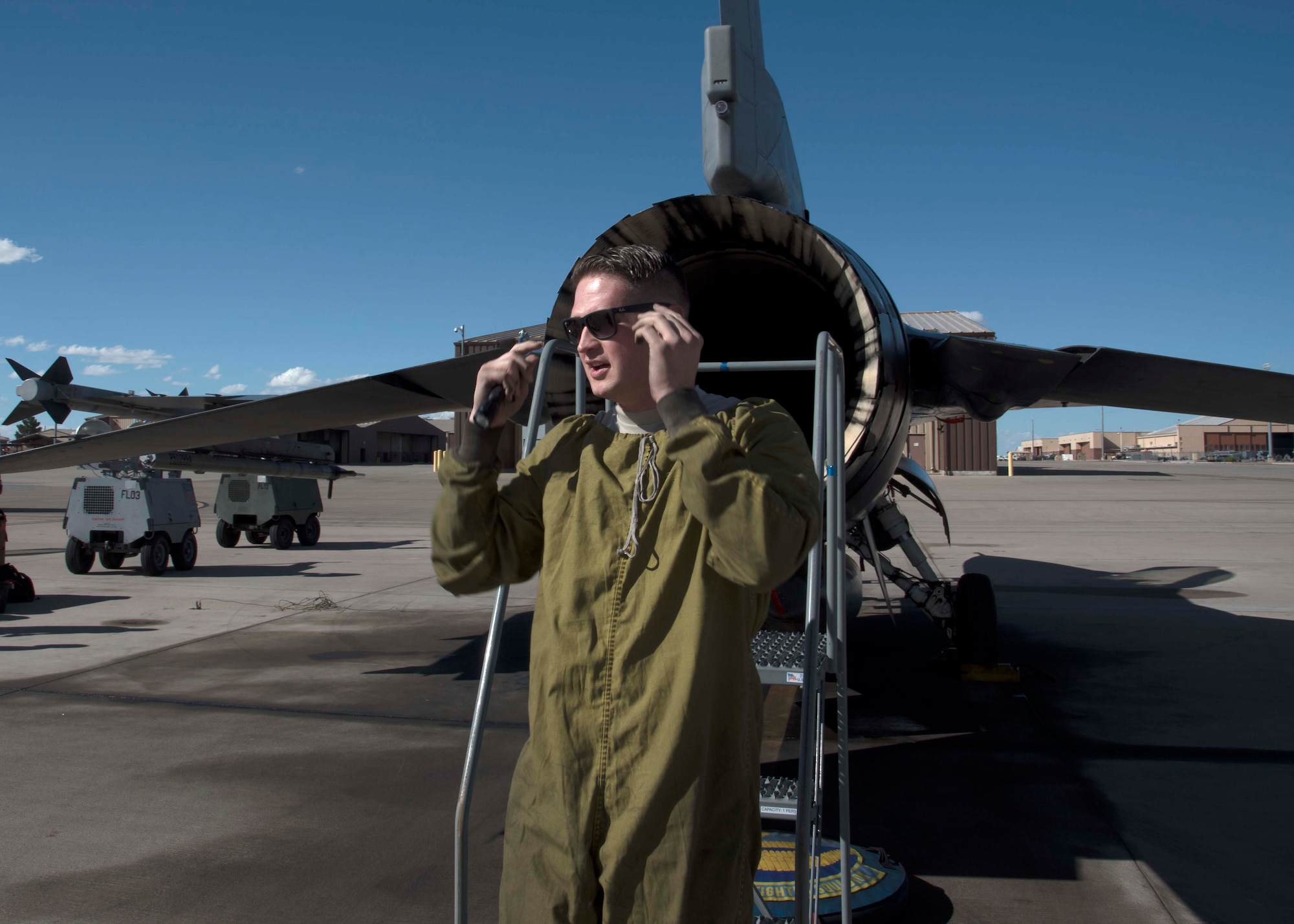 Tech. Sgt. Brandon Brittain, 311th Aircraft Maintenance Unit Dedicated Crew Chief, puts on sunglasses after climbing out of an F-16 Fighting Falcon exhaust Oct. 4 on Holloman Air Force Base, N.M. As a DCC, Brittain is assigned to a specific aircraft, and is responsible for all flight essential maintenance on his aircraft. (U.S. Air Force photo by Airman 1st Class Kindra Stewart)
