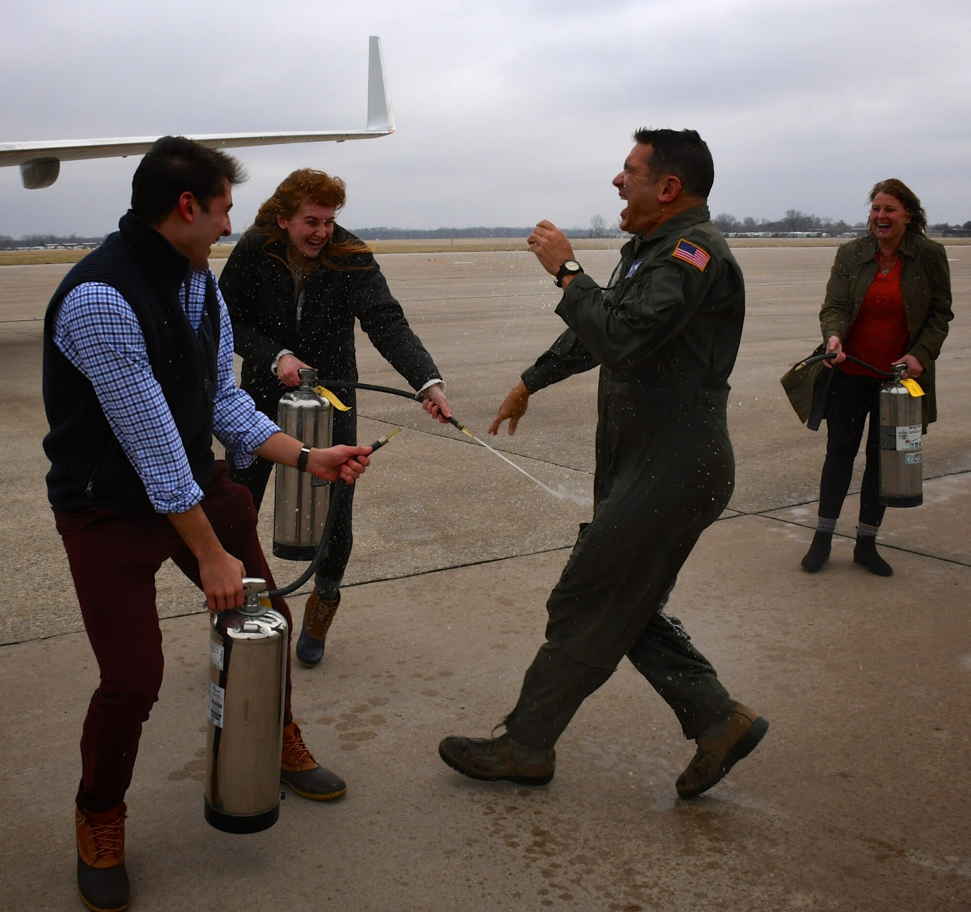 The outgoing commander of the 932nd Airlift Wing, Col. Raymond Smith, Jr., is sprayed with water by his family as he steps off the C-40 aircraft one last time.  His last training flight, also known as the "fini flight", occurred Dec. 21, 2018, at Scott Air Force Base, Illinois.  It was a bitterly cold day with temperatures in the 20's, but Smith braved the cold as family and friends gave him special congratulations water treatment as he leaves his current command of the "Gateway Wing".  He will take on new opportunities within United States Transportation Command.  In his time with the Illinois unit, he also served as the Operations Group commander.  The 932nd Airlift Wing is the only Air Force Reserve unit flying the C-40 plane in Illinois.  (U.S. Air Force photo by Lt. Col. Stan Paregien)