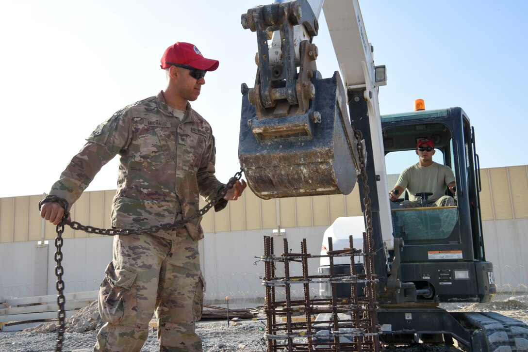 Tech. Sgt. Nathan Michaud, 557th Expeditionary Rapid Engineer Deployable Heavy Operational Repair Squadron, Engineering pavement and equipment operator, ties a chain to an excavator during construction of Air Field Damage repair equipment warehouse, Dec. 23, 2018 at Al Dhafra Air Base, United Arab Emirates.