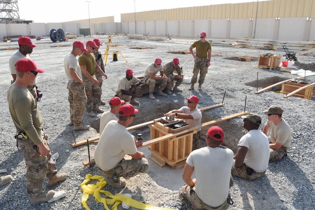 Staff Sgt. Thomas Findlay, 557th Expeditionary Rapid Engineer Deployable Heavy Operational Repair Squadron, engineering assistant, explains the foundation configuration during construction of Air Field Damage repair equipment warehouse, Dec. 23, 2018 at Al Dhafra Air Base, United Arab Emirates.