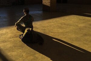 A soldier meditates in an empty room.