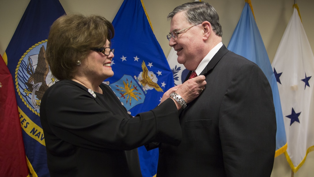 Karen Callahan attaches a retirement pin on her husband, Timothy Callahan, executive director of Contracts at the Defense Contract Management Agency, at his retirement ceremony at Fort Lee, Virginia, Jan. 31. (DCMA photo by Elizabeth Szoke)