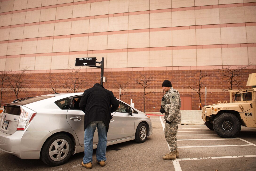 A guardsman stands next to a parked car.