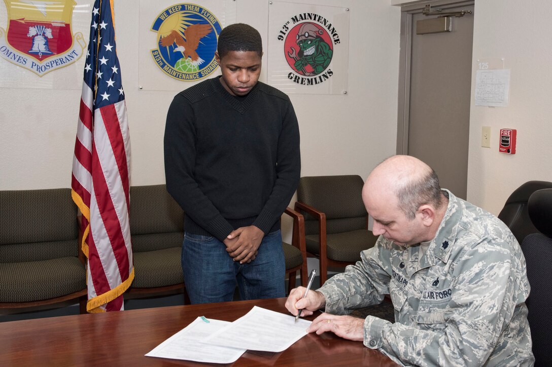 U.S. Air Force Reserve Senior Airman Derrick Barnes, a crew chief assigned to the 913th Maintenance Squadron, looks on as Lt. Col. Paul Centinaro, commander, 913 MXS, signs his re-enlistment paperwork at Little Rock Air Force Base, Ark., Jan. 31, 2018. Barnes made the commitment to serve his country for an additional six years. (U.S. Air Force photo by Master Sgt. Jeff Walston/Released)