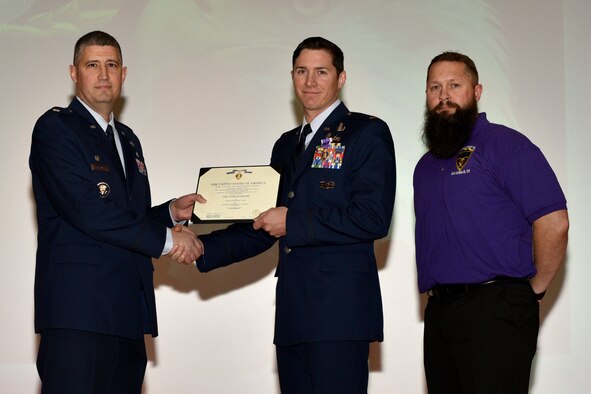 U.S. Air Force Lt. Col. Kenneth Stremmel, 315th Training Squadron commander, presents the Purple Heart certificate to 2nd Lt. Daniel Hipps, 315th TRS trainee, with Military Order of the Purple Heart Chapter 740 Commander, Chris Doggett during, the 315th graduation ceremony in the Base Theater on Goodfellow Air Force Base, Texas, Jan. 31, 2018. Hipps, received the Purple Heart for injuries he received while on deployment in Afghanistan. (U.S. Air Force Photo by Senior Airman Randall Moose/Released)