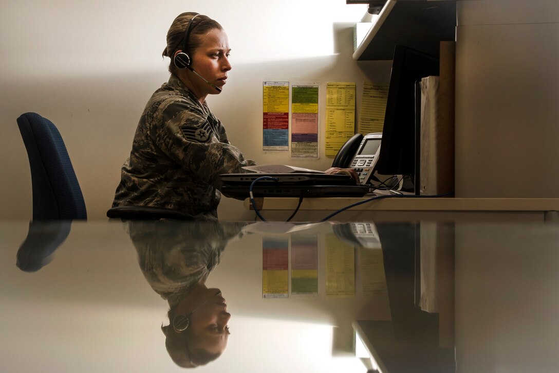 An airman helps customers over the phone from a desk.