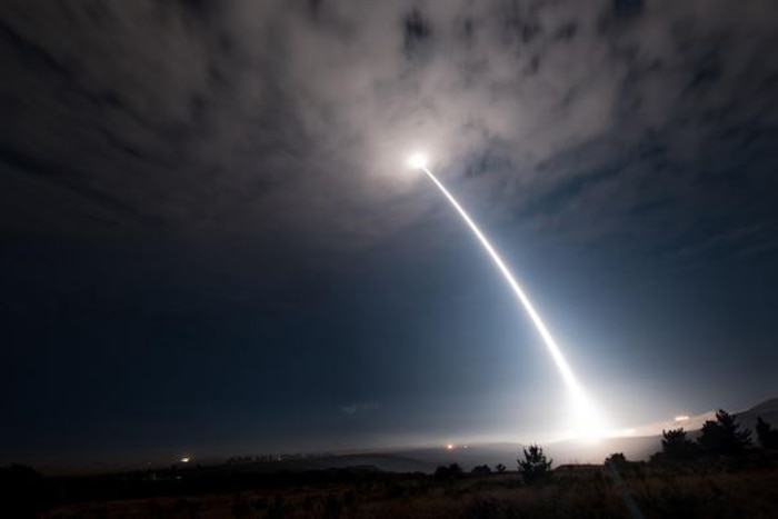 A missile launches against a midnight blue sky.