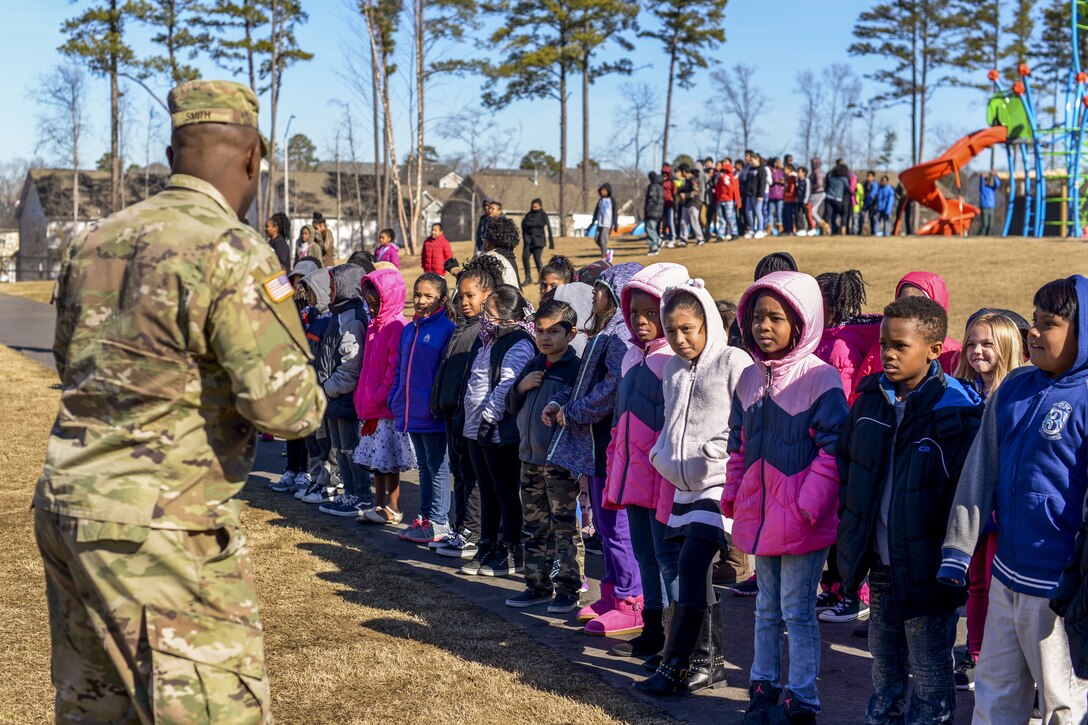 A soldiers talks to elementary students at a school.