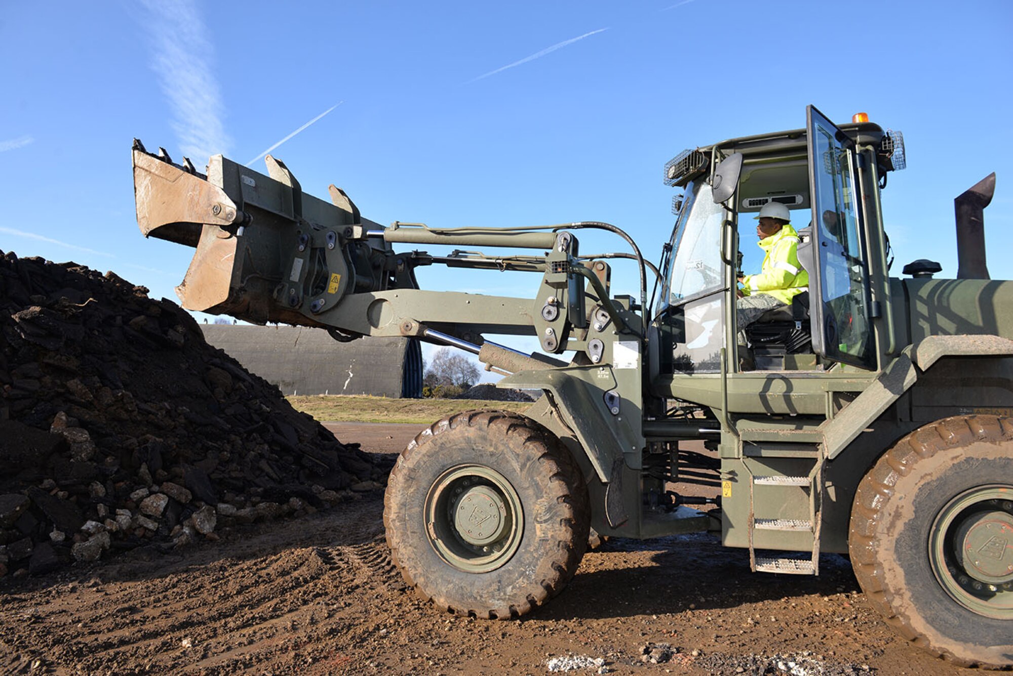 U.S. Air Force Airman 1st Class Tyler Alfred, 100th Civil Engineer Squadron pavements and equipment apprentice, operates a British Army front end loader, as he empties broken concrete onto a stockpile at Rock Barracks, Woodbridge, England, Jan. 25, 2018. U.S. Air Force Airmen from the 100th Civil Engineer Squadron pavements and equipment flight spent a week working alongside British Army engineers from the 23 Parachute Engineer Regiment, training their NATO partners in airfield damage repair. The Airmen and soldiers each had the opportunity to use each other’s heavy equipment and working practices. (U.S. Air Force photo by Karen Abeyasekere)