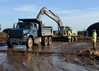 U.S. Air Force Staff Sgt. William Baynard, 100th Civil Engineer Squadron pavements and equipment supervisor, operates an excavator and loads a dump truck driven by a British Army Soldier from the 23 Parachute Engineer Regiment, as U.S. Airman 1st Class Brandon Monroe, 100th CES pavement and equipment apprentice, directs the truck into position at Rock Barracks, Woodbridge, England, Jan. 25, 2018. American dump trucks from RAF Mildenhall, and British excavators and loaders were used by the allied forces to remove concrete and asphalt in preparation for the building of a training area. (U.S. Air Force photo by Karen Abeyasekere)