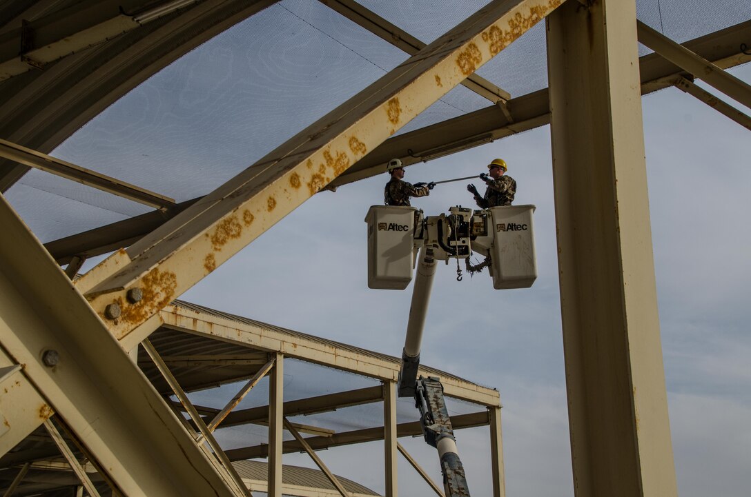 U.S. Air Force Senior Airman Robert Haehnel and Staff Sgt. Brandon Hutchinson 380th Expeditionary Civil Engineer Squadron electrical specialists, install new energy efficient light-emitting diodes (LED) light bulbs on the flightline of Al Dhafra Air Base, United Arab Emirates, Jan. 29, 2018. By making the best use of its energy resources, the Air Force achieves an edge toward ensuring operational supremacy and moves towards its strategic vision to enhance mission assurance through energy assurance. (U.S. Air National Guard photo by Staff Sgt. Colton Elliott)