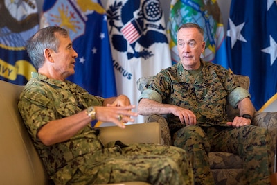 Two military leaders sit on a couch and chair talking.