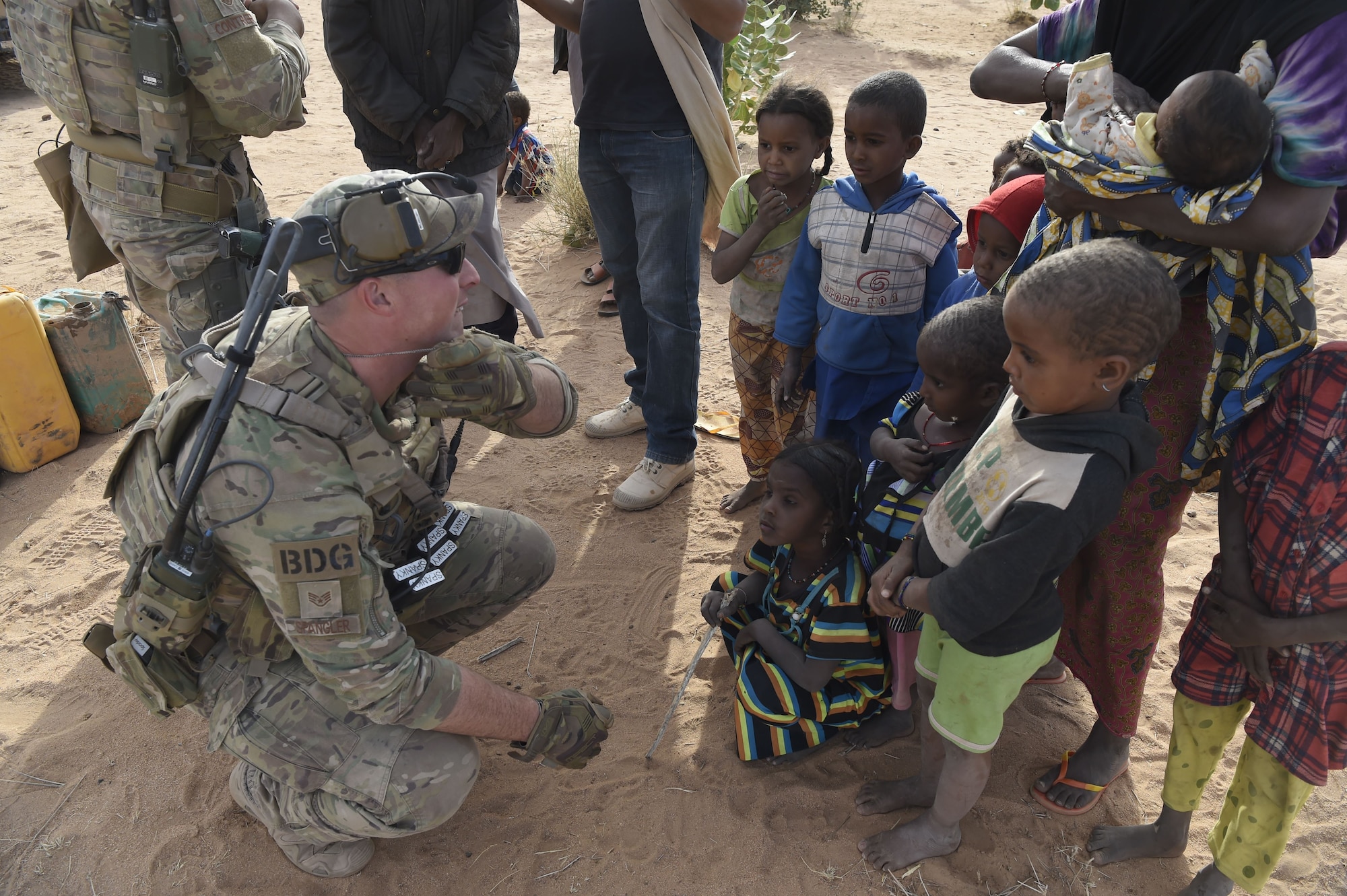 U.S. Air Force Tech Sgt. Douglas N. Spangler, 822nd Expeditionary Base Defense Squadron Security Forces squad leader, speaks to children from a nearby village outside of Air Base 201, Niger, Dec. 11, 2017. Spangler led a 13-member patrol team to find a missing two-year-old girl who was lost for six hours outside of Air Base 201. (U.S. Air Force photo by Staff Sgt. Joshua Dewberry)