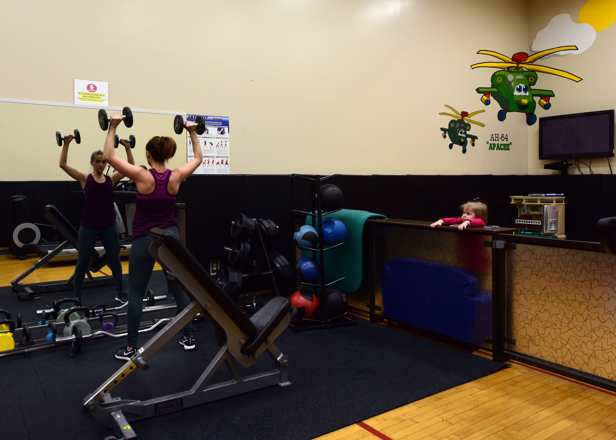 A member of Team Whiteman uses the parent/child activity room in the Fitness Center at Whiteman Air Force Base, Mo., Jan. 24, 2018. Exercise equipment such as treadmills and assorted weights are available to use while children play in an enclosed area with toys and playsets. (U.S. Air Force photo by Staff Sgt. Danielle Quilla)