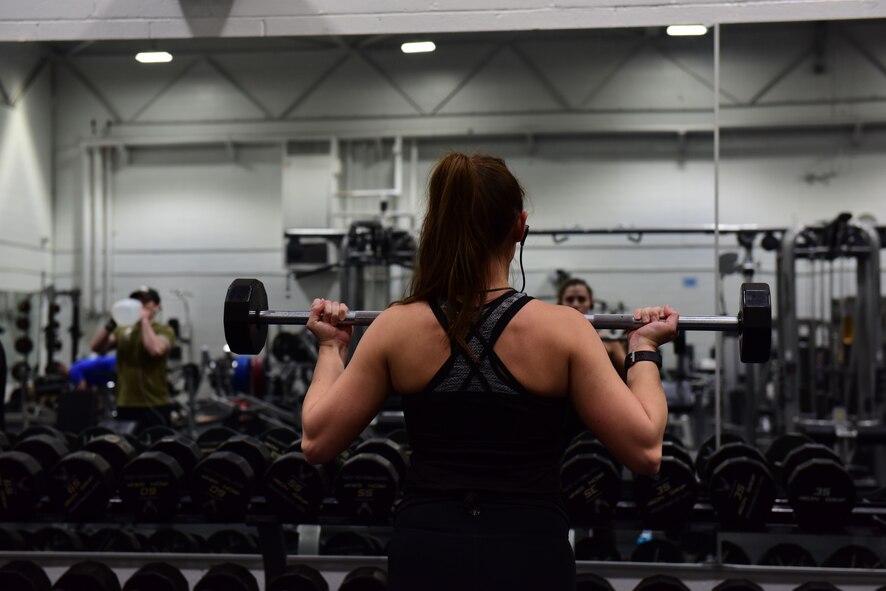 Lisa Webster, an Air Force spouse, performs a barbell curl in the Fitness Center weight room at Whiteman Air Force Base, Mo., Jan. 24, 2018. Active duty, reservists, guardsmen and dependents over the age of 16 have the option of registering for 24-hour access to use the equipment outside of the normal hours of operation. (U.S. Air Force photo by Staff Sgt. Danielle Quilla)