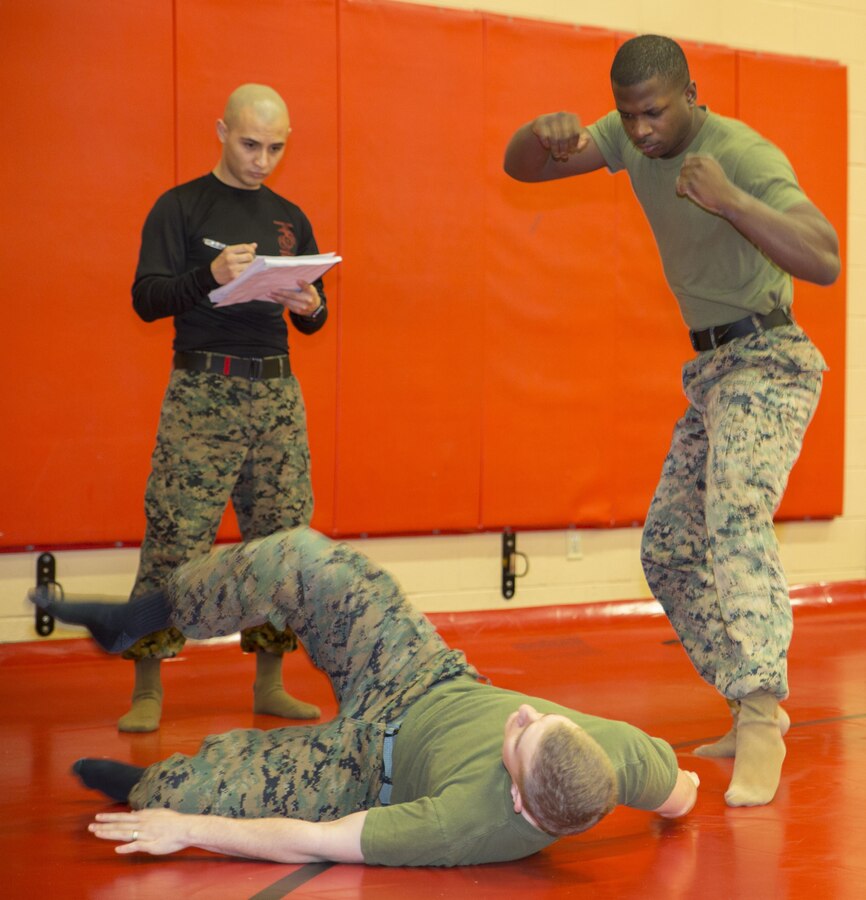 Cpl. Cody Marx, legal services non-commissioned officer, U.S. Marine Corps Forces Command, demonstrates a proper break-fall technique after a shoulder throw from Sgt. Lloyd Williams, assistant landing force operational reserve material
warehouse chief, G4, MARFORCOM, while Staff Sgt. Frankie Ruiz, warehouse chief, G4, MARFORCOM, observes the execution during a Marine Corps Martial Arts Program belt exam at Hopkins Hall Gym aboard Camp Allen, in Norfolk, Va.,
Jan. 31. Marx had to demonstrate several techniques from lower belt levels before being tested on his green belt moves. (Official U.S. Marine Corps photo by Chris Jones/Released)