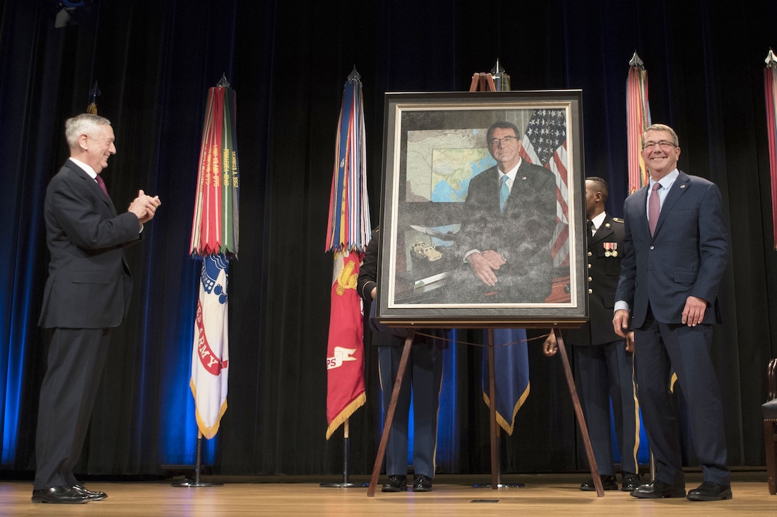 Two defense leaders stand on opposite sides of a portrait during a ceremony at the Pentagon.