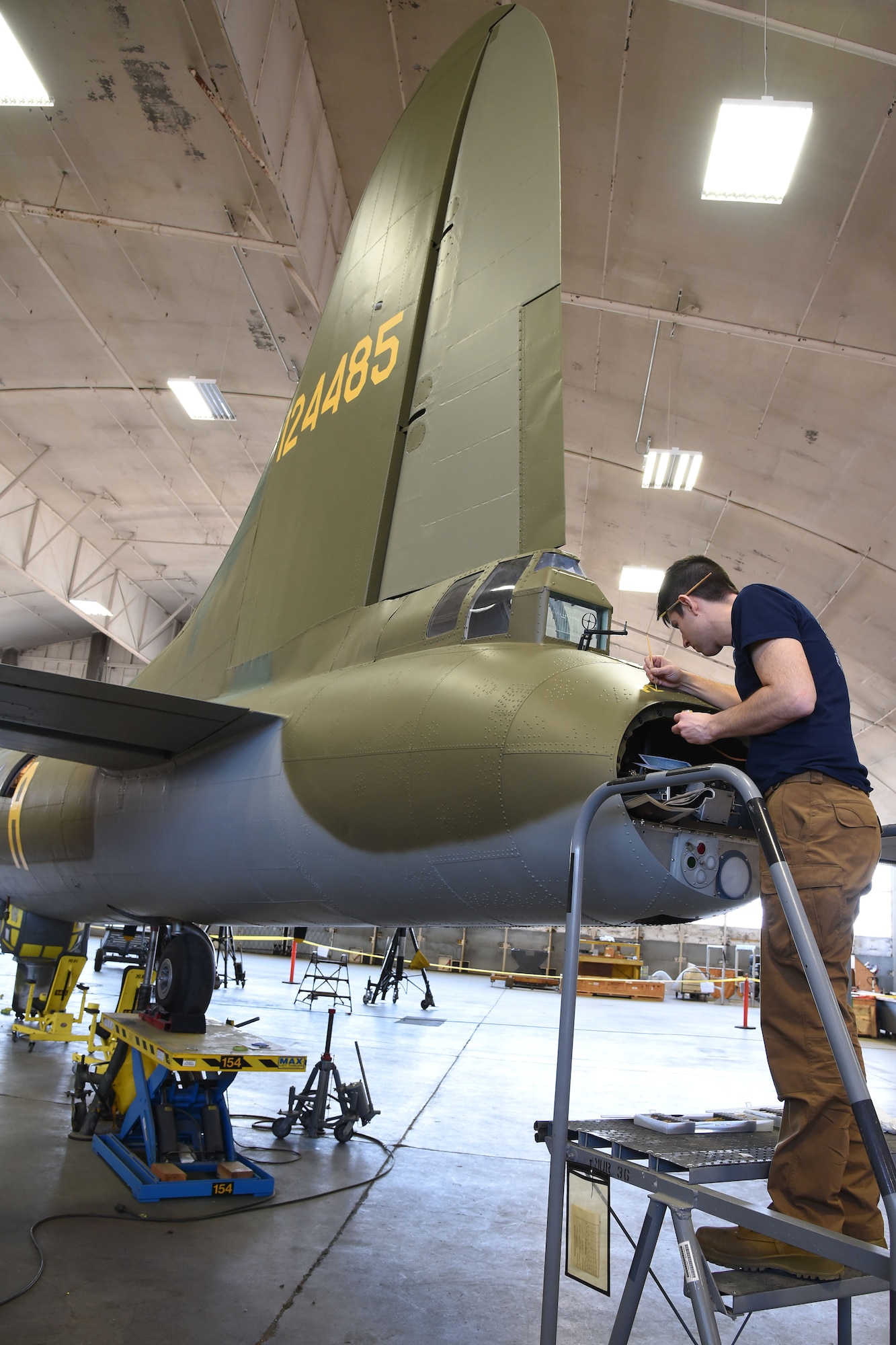 (02/01/2018) Museum restoration specialist Casey Simmons paints the names Pete and Repeat on the tail gun position of the Boeing B-17F Memphis Belle during the restoration process. SSgt. John Quinlan, the tail gunner of the Memphis Belle crew, named the guns Pete and Repeat during WWII. Quinlan also received credit for shooting down one German fighter which is represented by the swastika. (U.S. Air Force photo by Ken LaRock)