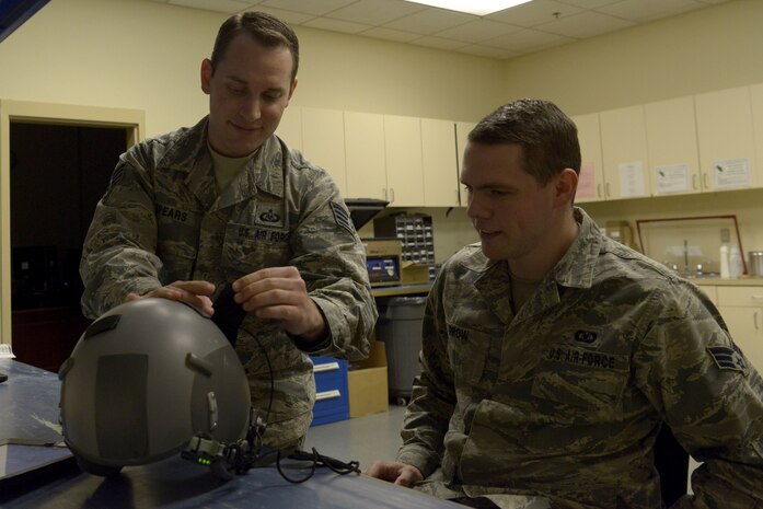 U.S. Air Force Staff Sgt. Brian Spears, left, 437th Operations Support Squadron aircrew flight equipment lead trainer, shows Air Force U.S. Air Force Senior Airman Matthew Prow, 437th OSS aircrew flight equipment journeyman, proper inspection procedures for a flight helmet Feb. 1, 2018.