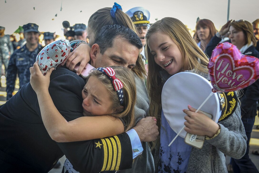 A Navy commander hugs his family as his ship returns to port.
