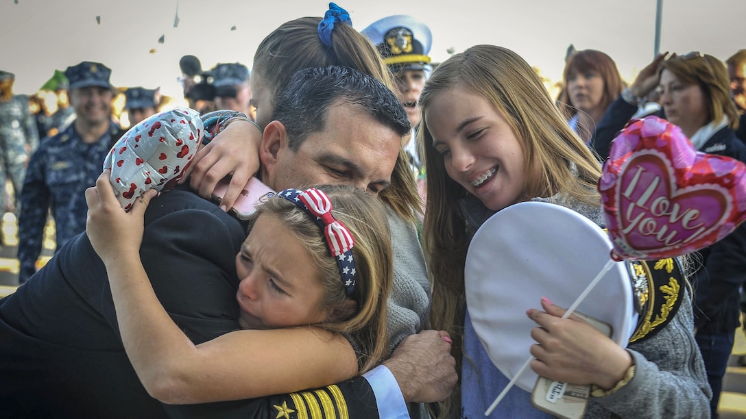 A Navy commander hugs his family as his ship returns to port.