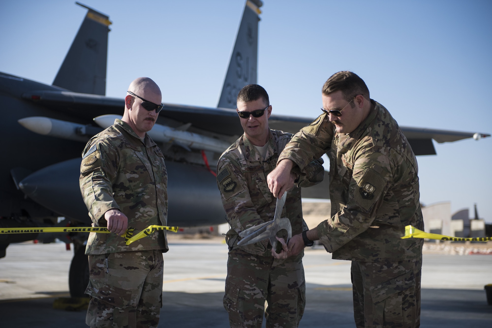 Brig. Gen. Kyle Robinson, 332d Air Expeditionary Wing commander (center), joins Capt. Nathan Smith, 557th Expeditionary RED HORSE Squadron Director of Operations (right) in opening the taxiway delta fighter apron expansion February 2, 2018 in Southwest Asia. Members of the 557th RHS poured 3,742 cubic meters of concrete over 18 days, providing 165,000 square feet of improved aircraft parking and taxiways needed to sustain increased combat operations.