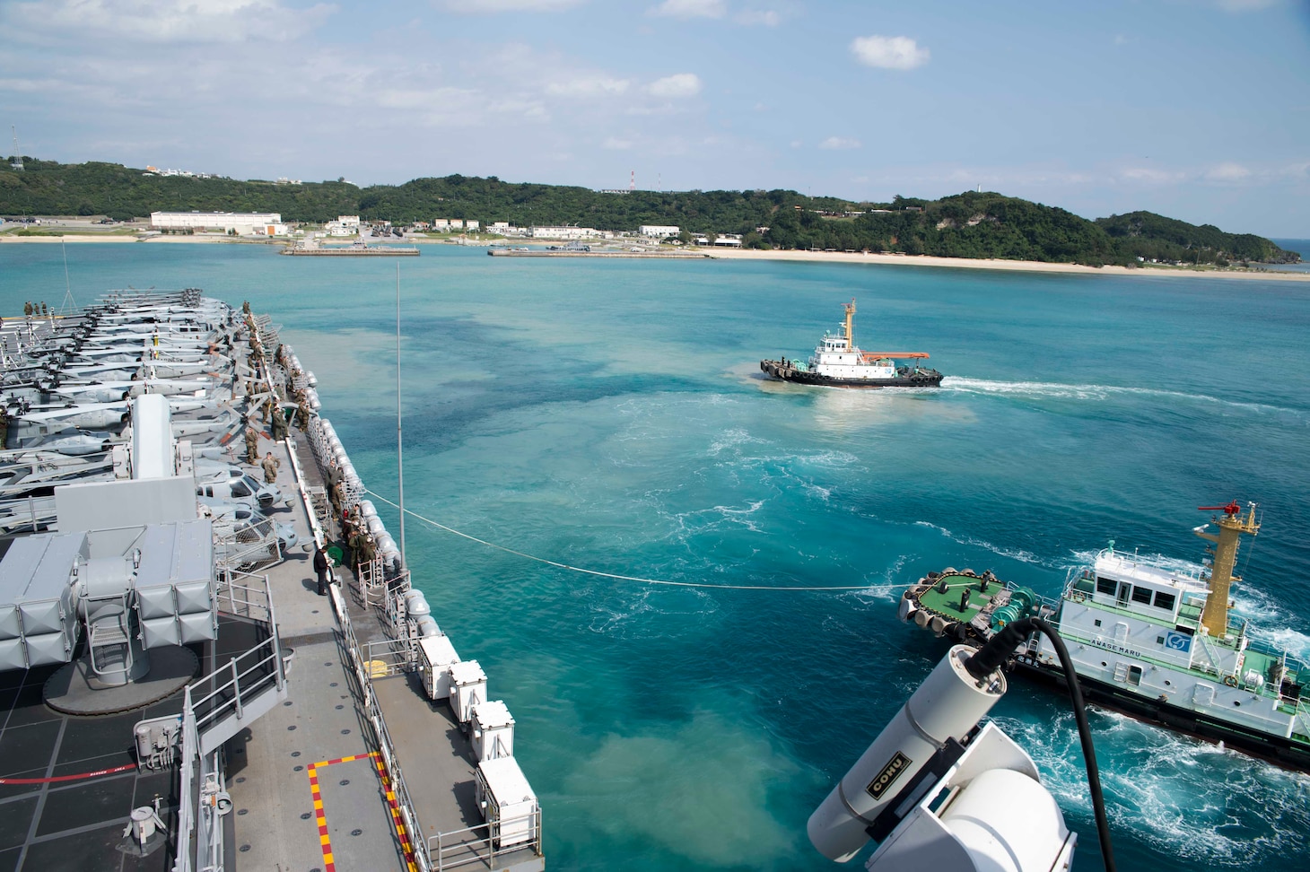 180202-N-XK809-013 WHITE BEACH, Okinawa (Feb. 2, 2018) A tug boat guides the amphibious assault ship USS Bonhomme Richard (LHD 6) away from the pier during the ship’s departure from White Beach Naval Facility, Okinawa. Bonhomme Richard is operating in the Indo-Asia-Pacific region as part of a regularly scheduled patrol and provides a rapid-response capability in the event of a regional contingency or natural disaster. (U.S. Navy photo by Mass Communication Specialist 2nd Class William Sykes/Released)