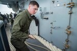 HITE BEACH, Okinawa (Feb. 2, 2018) Lance Cpl. Brandon Rudde, from Independence, Ky., heaves a line during sea and anchor detail aboard the amphibious assault ship USS Bonhomme Richard (LHD 6) as the ship departs White Beach Naval Facility, Okinawa.