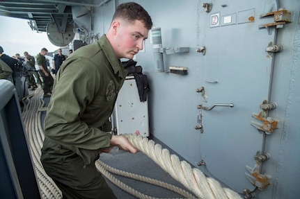 HITE BEACH, Okinawa (Feb. 2, 2018) Lance Cpl. Brandon Rudde, from Independence, Ky., heaves a line during sea and anchor detail aboard the amphibious assault ship USS Bonhomme Richard (LHD 6) as the ship departs White Beach Naval Facility, Okinawa.