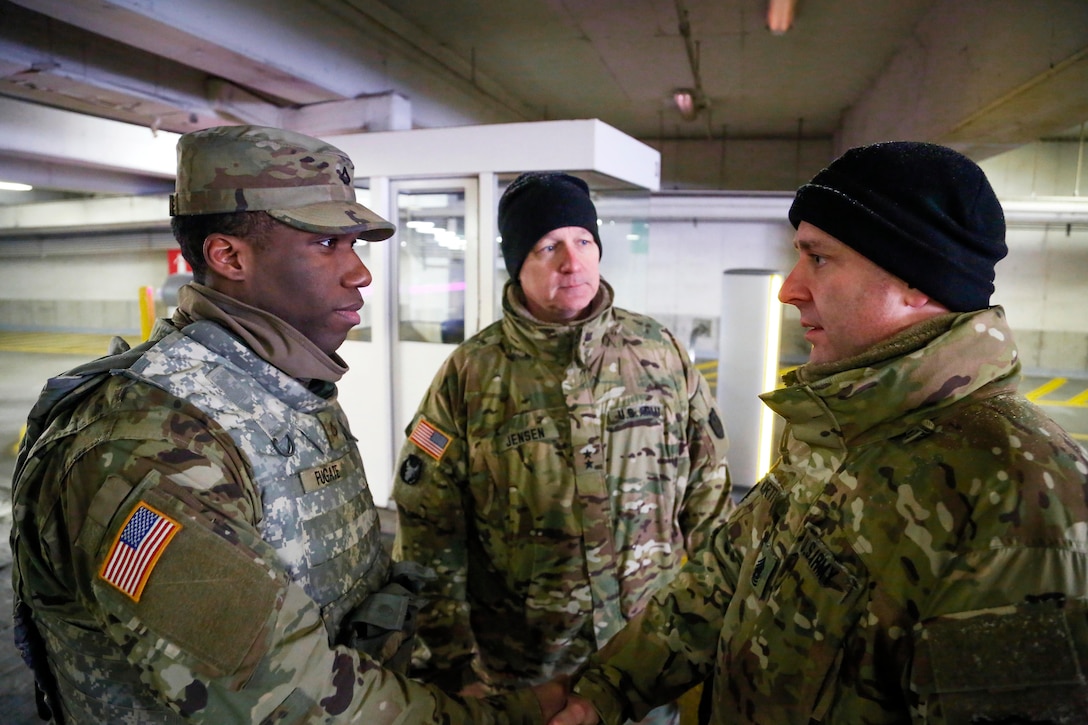 Three soldiers stand in a parking garage.