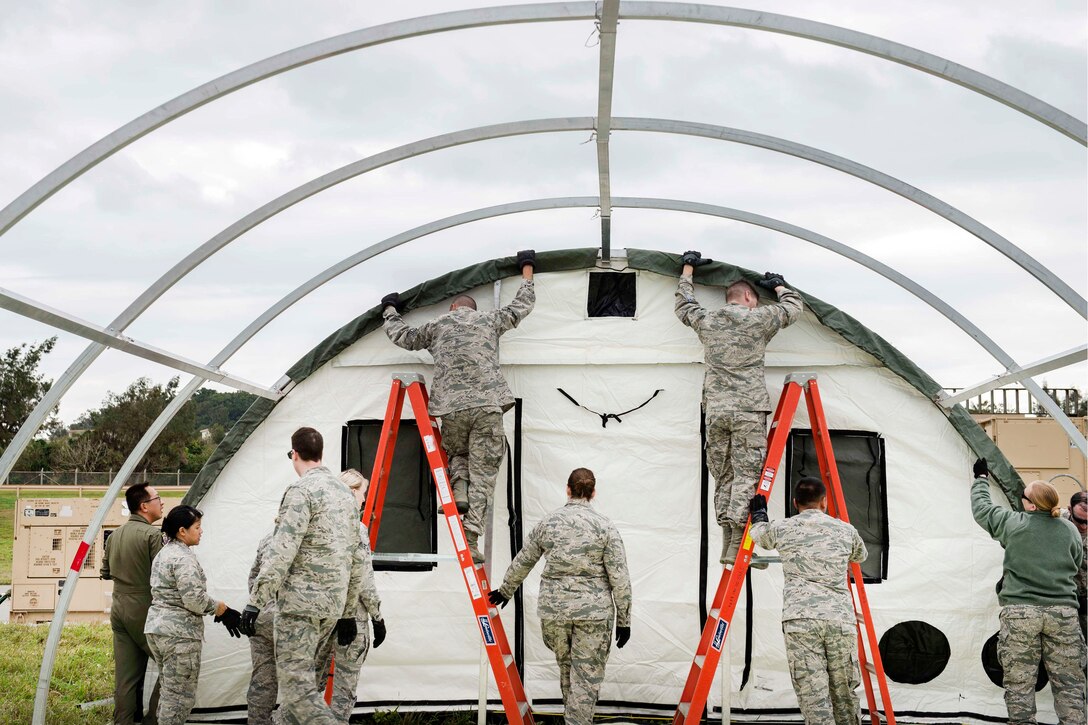 Airmen assemble the structural framing for a tent near the flightline.