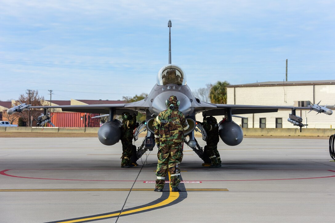 A guardsman wearing a chemical suit conducts a systems check on an aircraft.