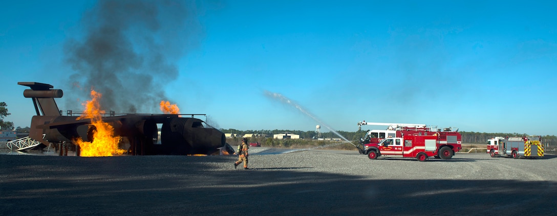 Air Force airmen use fire hoses to put out a simulated aircraft fire.