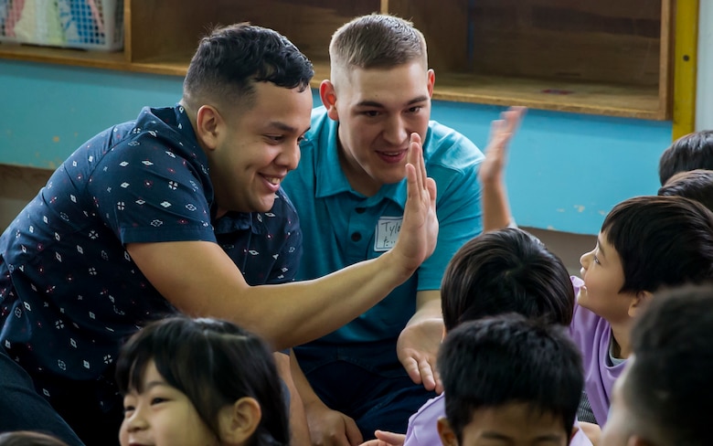 U.S. Marine Corps Lance Cpl. Headley Hall (left) and Petty Officer 3rd Class Tylor Tharp (right) high five children during a visit to Namisato Preschool in Okinawa, Japan, Jan. 30, 2018. Marines visited the school for a community relations event that helps the children learn basic English. Hall, a Chicago native, is an administrative clerk and Tharp, a St. Augustine, Florida native, is a religious program specialist. Both Marines are with Headquarters and Service Company, 3rd Battalion, 3rd Marine Regiment, 3rd Marine Division. The Marines continue fostering relations with the local population and building bonds with allies.