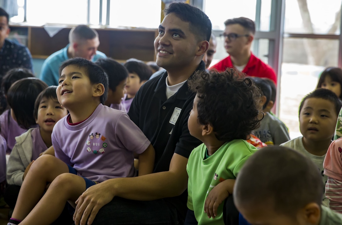 U.S. Marine Corps Cpl. Mac Sautia sits with children during a visit to Namisato Preschool in Okinawa, Japan, Jan. 30, 2018. Marines visited the school during a community relations event to help children learn basic English. Sautia, an Oceanside, California native, is a radio technician with Headquarters and Service Company, 3rd Battalion, 3rd Marine Regiment, 3rd Marine Division. Marines continue fostering relations with the local population and building bonds with allies.