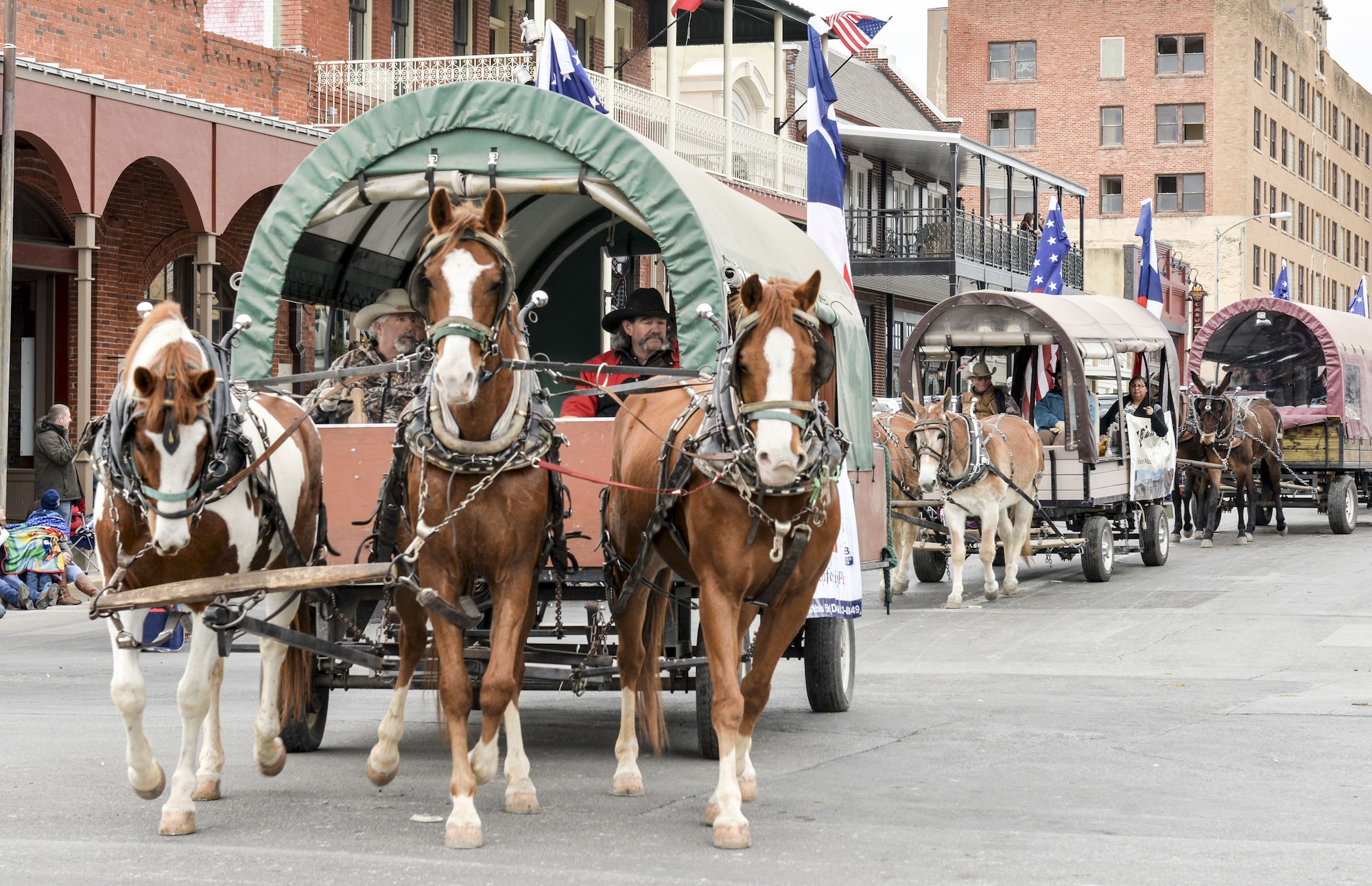 Members of the Santa Fe Trail Ride travel through historic downtown San Angelo, Texas during the rodeo parade, Feb. 3. 2018. The Santa Fe Trail Ride ended in San Angelo after a week-long ride of 25 covered wagons allowing participants to experience some of what travelling was like during the 1800s.  (U.S. Air Force photo by Aryn Lockhart/Released)