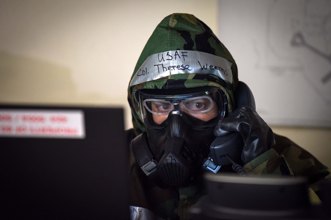 An airmen in protective gear looks at a computer monitor.