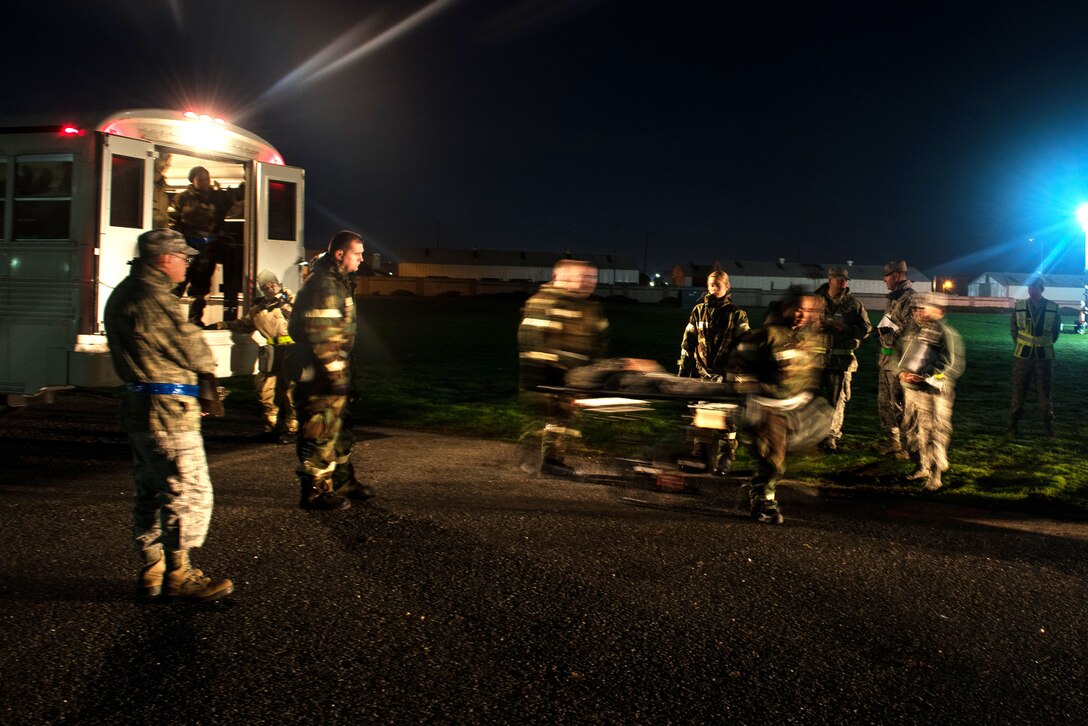 Airmen move simulated patients on a stretcher.