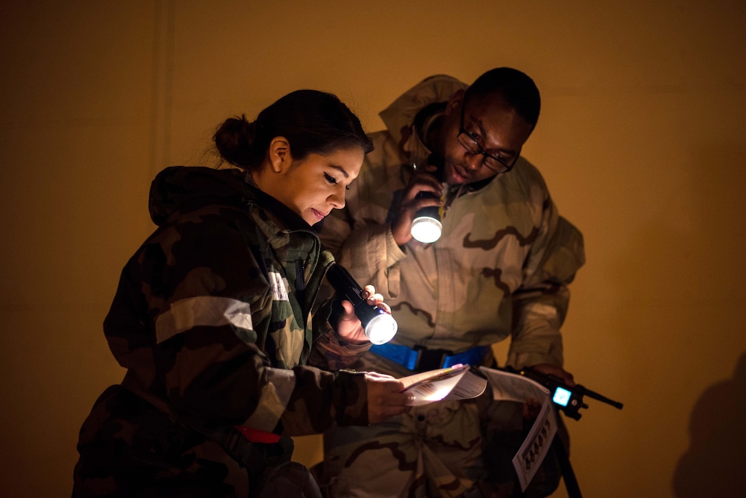 Two airmen use flashlights to read.