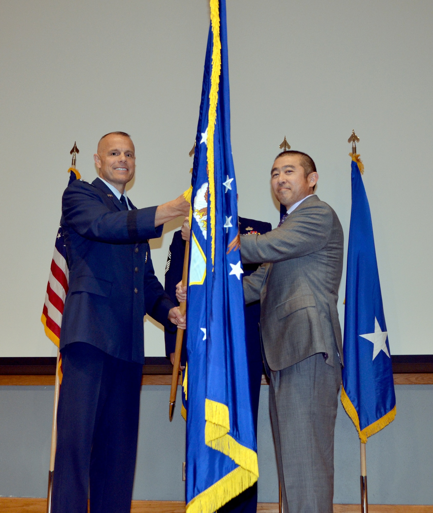 Maj. Gen. Bradley D. Spacy, commander of the Air Force Installation and Mission Support Center, passes the unit flag to Edwin H. Oshiba