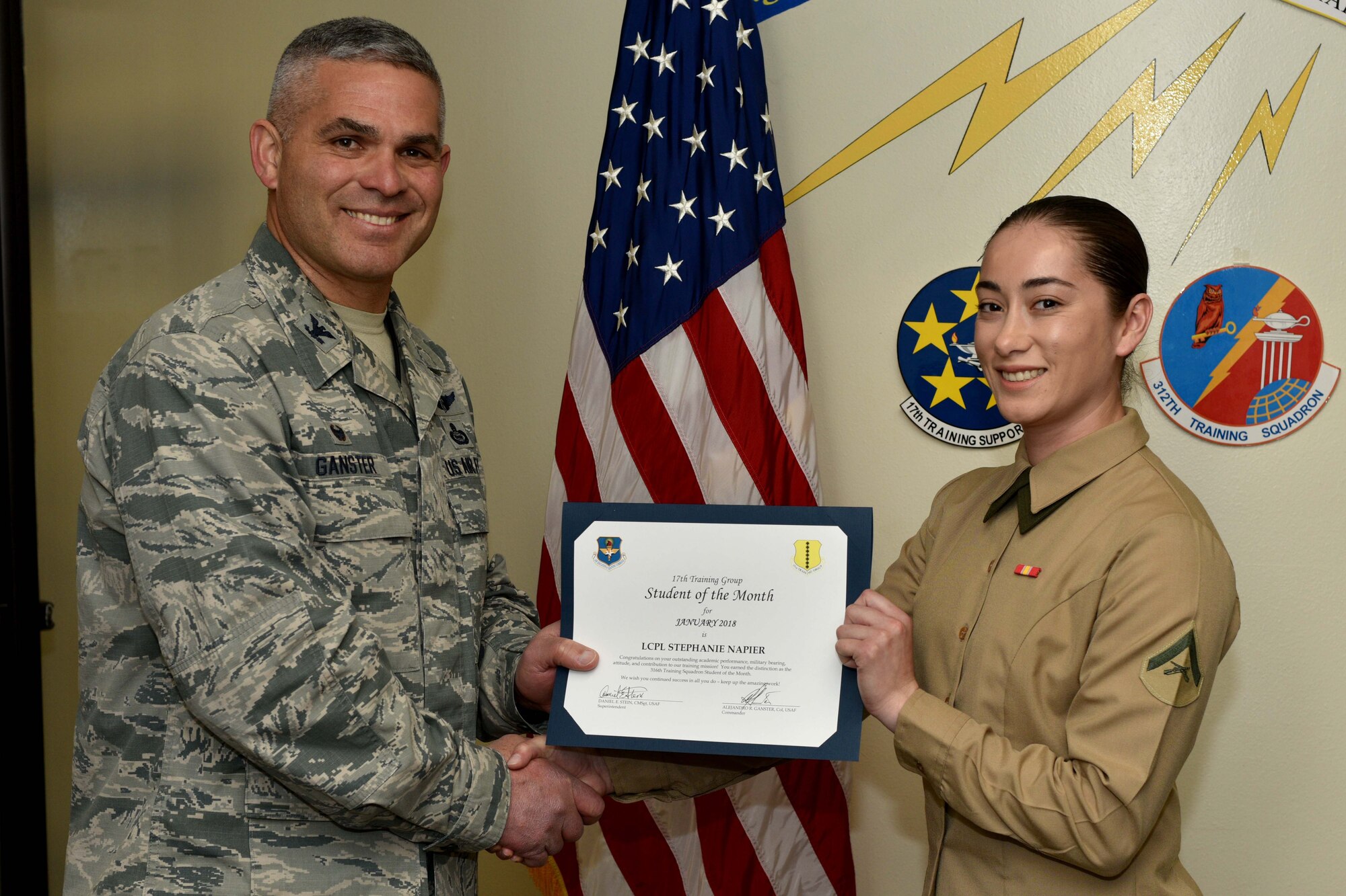 U.S. Air Force Col. Alex Ganster, 17th Training Group commander, presents the 316th Training Squadron Student of the Month award for Jan. 2018 to U.S. Marine Corps Lance Cpl. Stephanie Napier, Marine Corps Detachment at Goodfellow trainee, in the Brandenburg Hall on Goodfellow Air Force Base, Texas, Jan. 2, 2018. The 316th Training Squadron’s mission is to conduct U.S. Air Force, U.S. Army, U.S. Marine Corps, U.S. Navy and U.S. Coast Guard cryptologic, human intelligence and military training.
