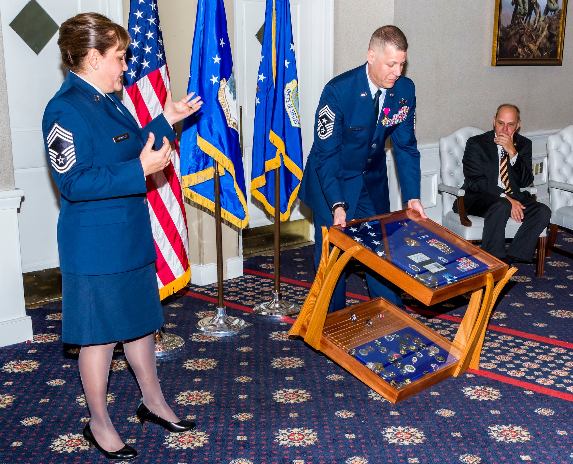 AFOSI Command Chief Master Sgt. #15, Christopher J. VanBurger, displays the two-tiered shadow box presented by his wife, Chief Master Sgt. Lizabeth VanBurger, as AFOSI Command Chief Master Sgt. #10, retired, Ray Carter looks on during Command Chief VanBurger's retirement ceremony at Quantico, Va., Jan. 26, 2018. (U.S. Air Force photo by Michael Hastings)