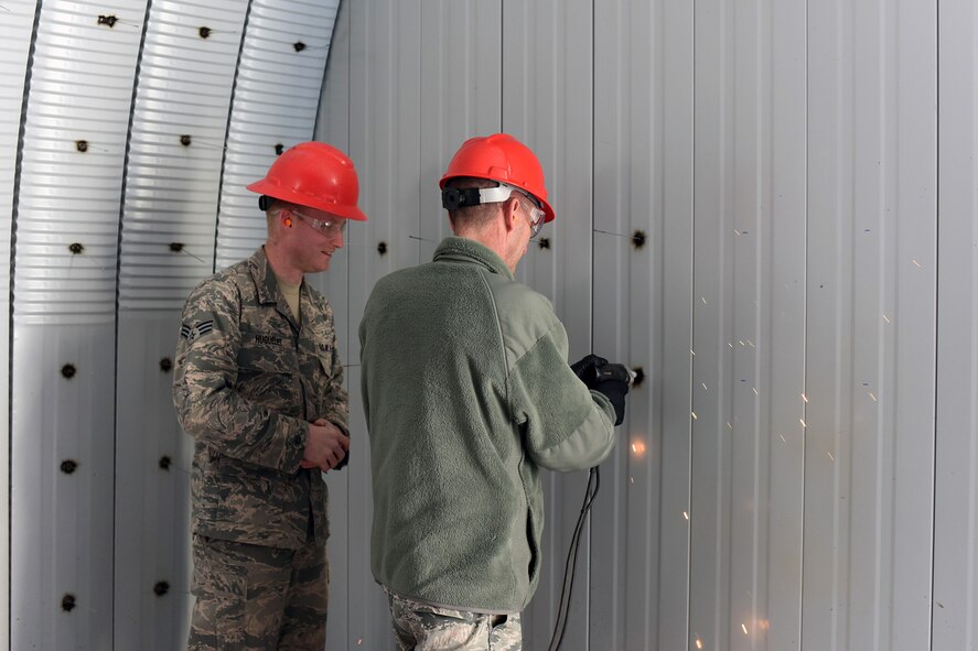 U.S. Air Force Maj. Gen. Scott J. Zobrist, right, 9th Air Force commander, welds a pin to support insulation for a K-Span storage facility at Malmstrom Air Force Base, Mont., while Senior Airman Seth Huguelet discusses welding techniques Jan. 25, 2018. Huguelet is among a team of 819th Rapid Engineer Deployable Heavy Operational Repair Squadron Engineers (RED HORSE) building a K-Space facility which will store RED HORSE equipment. RED HORSE Airmen capitalize on construction opportunities while at home to maintain proficiency for their overseas missions. (U.S. Air Force photo by Kiersten McCutchan)