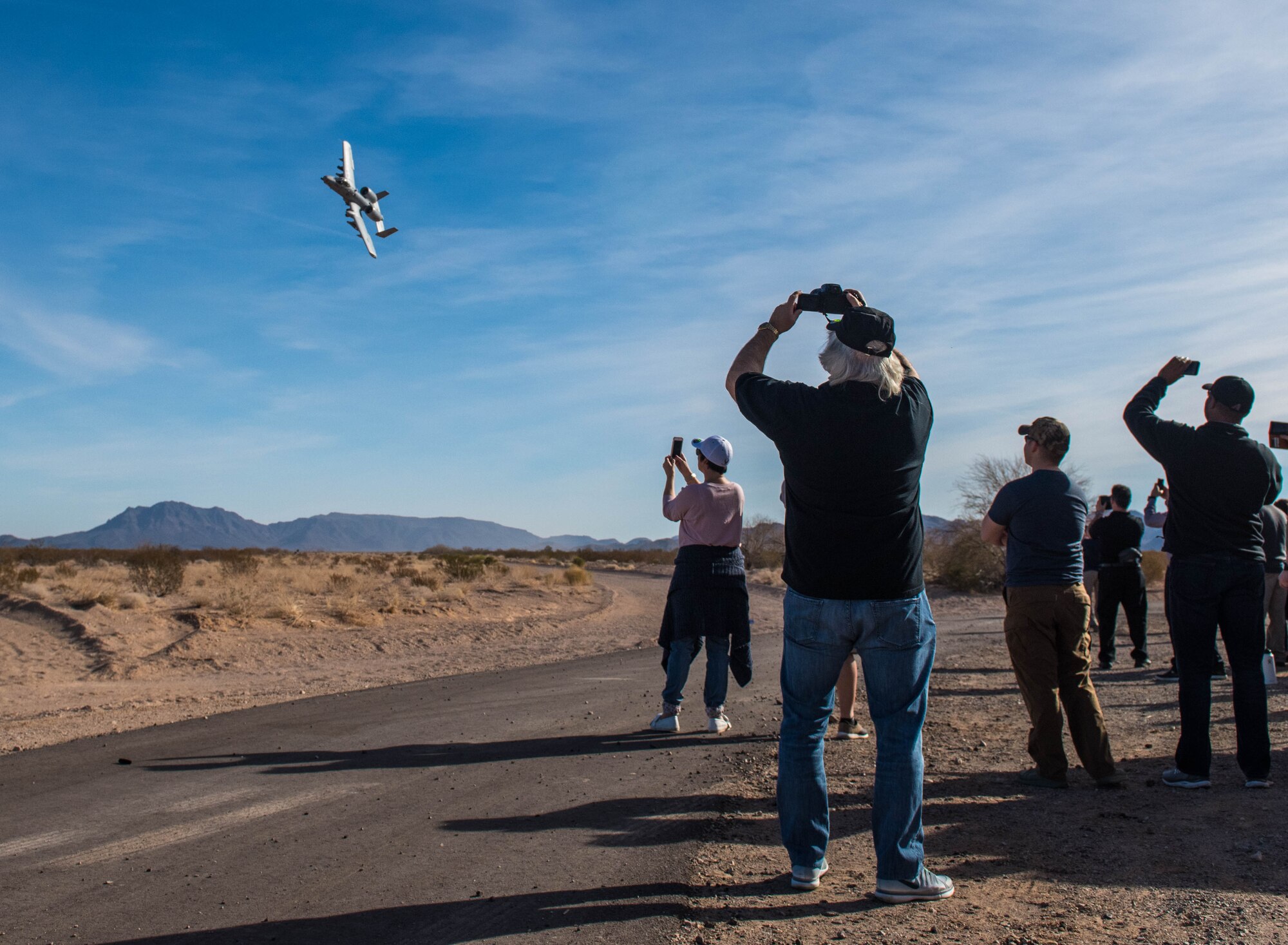Spectators watch as an A-10 Thunderbolt II flies over the Barry M. Goldwater Range in Gila Bend, Ariz., Feb. 1, 2018. Airspace over Luke Air Force Base as well as the BMGR was used for pilots to contest with one another in basic fighter maneuvers and air-to-surface attacks in an annual competition known as Haboob Havoc. (U.S. Air Force photo/Airman 1st Class Caleb Worpel)