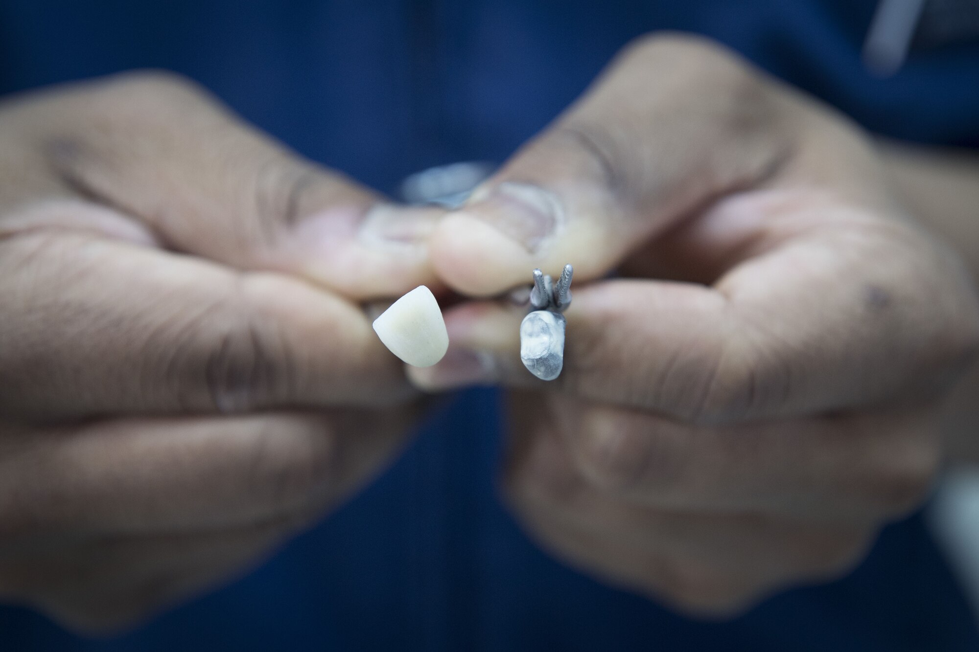 Staff Sgt. Bryan Holloway, 374th Dental Squadron dental lab technician, shows a finished hand-crafted ceramic porcelain on meatal tooth and the meatal core, Jan. 29, 2018, at Yokota Air Base, Japan.