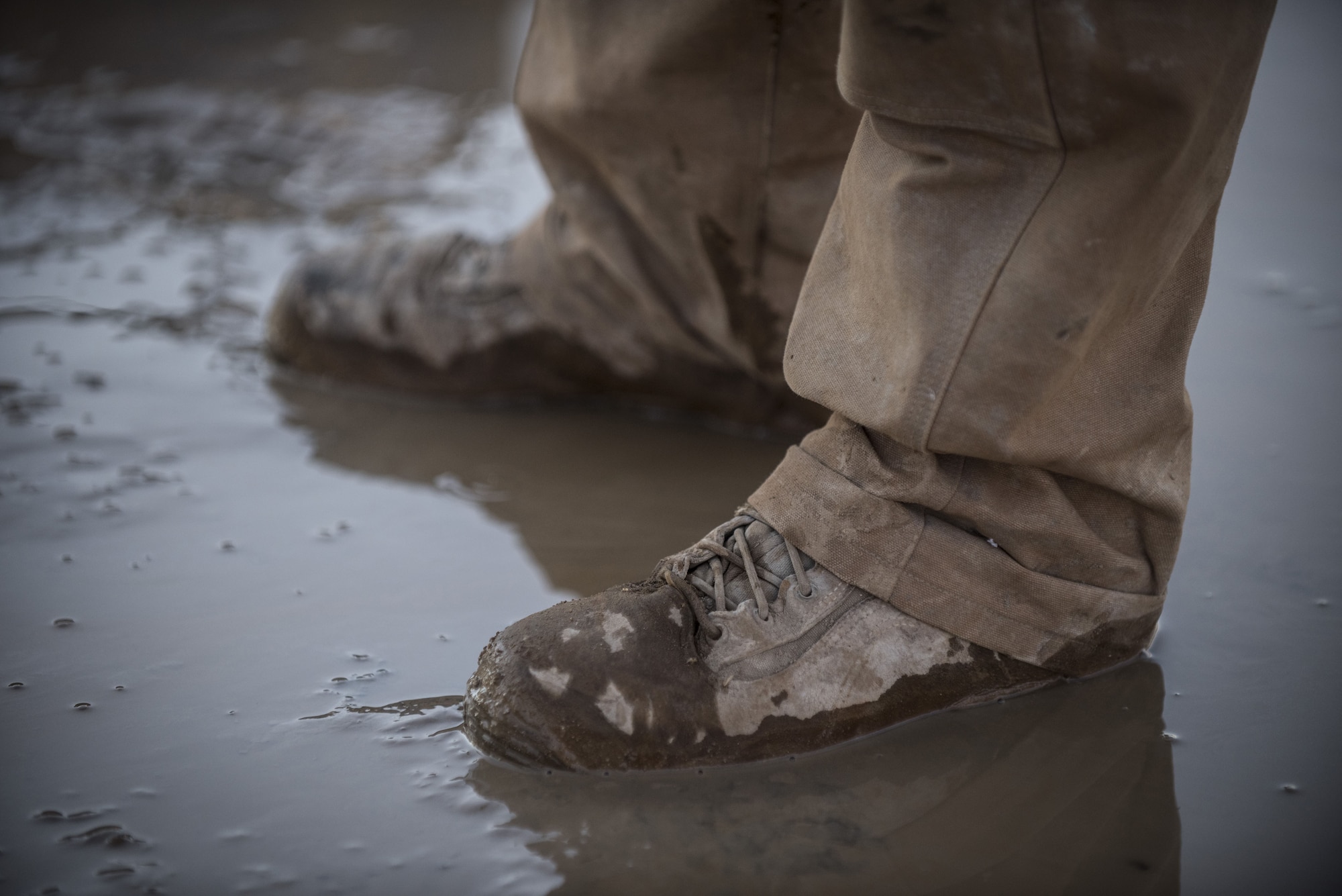 An Airman assigned to the 557th Expeditionary RED HORSE Squadron stand in a puddle of fresh groundwater on the site of a newly-drilled well January 31, 2018 at an undisclosed location in Southwest Asia. This 1,500 ft deep well, and two other like it, will provide potable water for future facilities as the coalition works to establish an enduring presence in the region. (U.S. Air Force photo by Staff Sgt. Joshua Kleinholz)