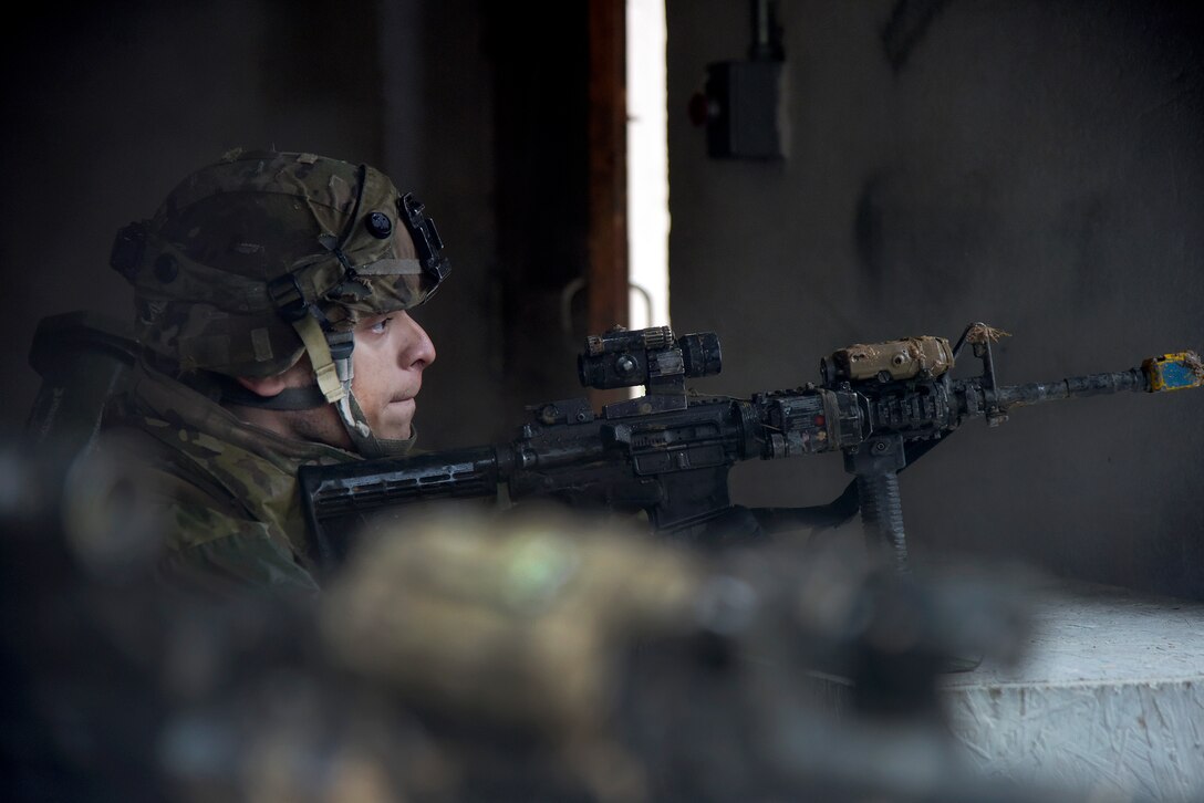 A soldier looks down a machine gun sight.
