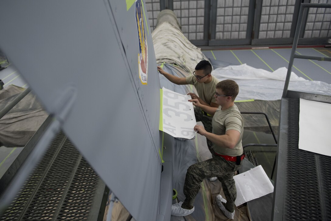 U.S. Air Force Airman 1st Class Roman Estrada, 20th Equipment Maintenance Squadron (EMS) corrosion apprentice, left, and Senior Airman Skylar Braden, 20th EMS corrosion journeyman, use stencils to measure where decals on an F-16CM Fighting Falcon would be placed at Shaw Air Force Base, S.C., Feb. 1, 2018.
