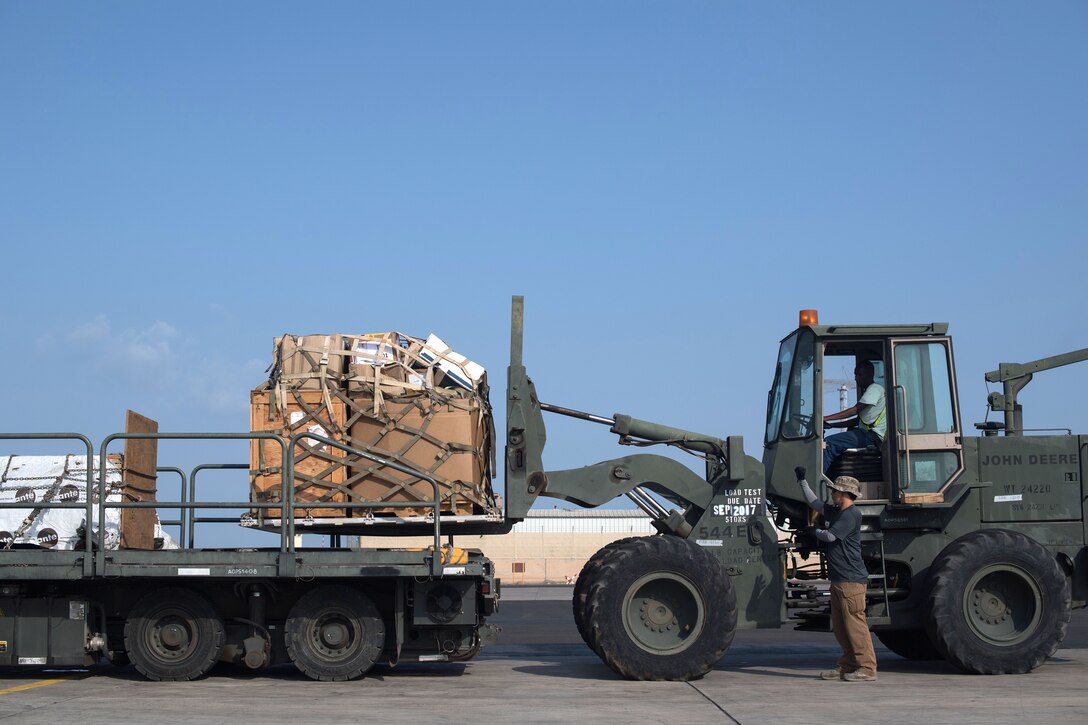 A forklift moves cargo off of a flatbed truck.